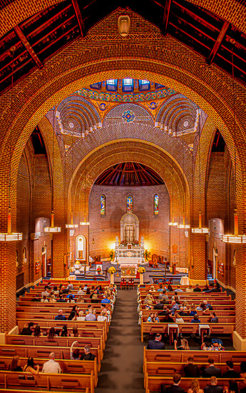 Brick church interior filled with people in pews.