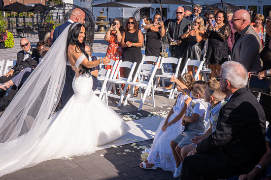 Bride gives thumbs up at outdoor wedding ceremony.