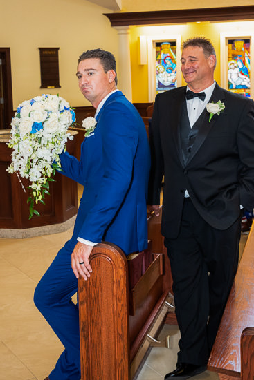 Groom and best man await wedding ceremony in church.