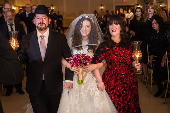 Jewish wedding procession with bride, parents, and candles.