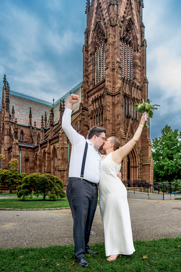 Newlyweds celebrate with a kiss in front of a church.