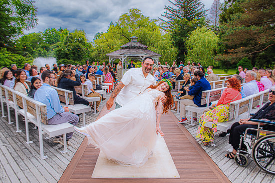 Newlyweds celebrate with guests at outdoor wedding ceremony.