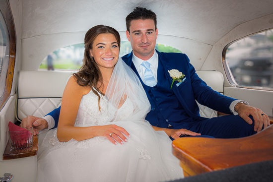 Newlyweds in limousine, smiling after wedding ceremony.