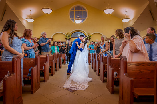 Newlyweds share a kiss as guests celebrate in church.