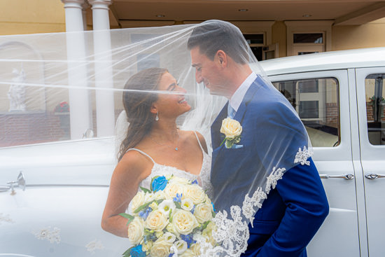 Newlyweds share a loving glance under a veil.