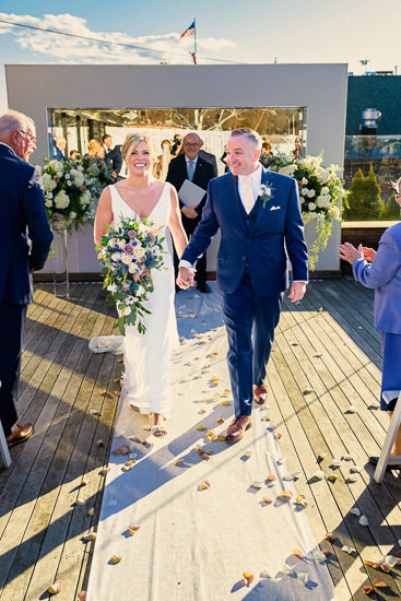 Newlyweds walk down the aisle, smiling, on their wedding day.
