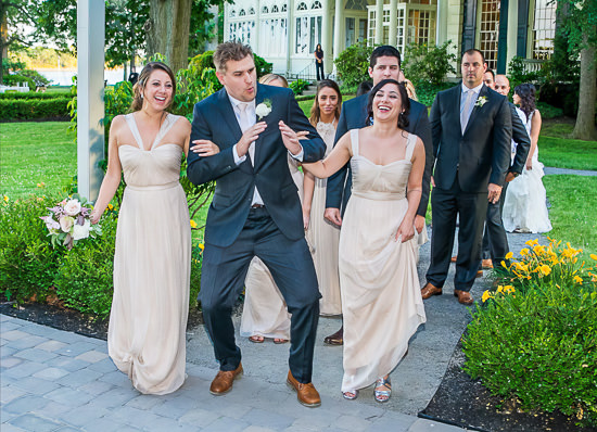 Wedding party joyfully enters reception, dancing and laughing.