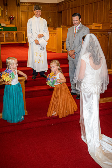 Wedding scene: bride, groom, flower girls, and officiant.
